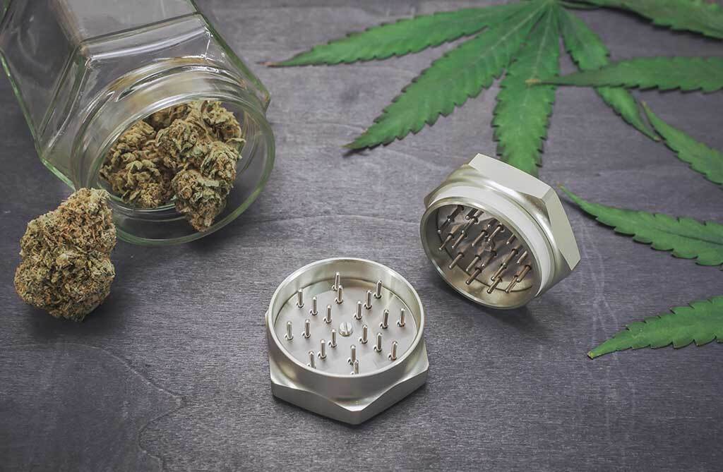 Marijuana buds and a grinder on black wood background.